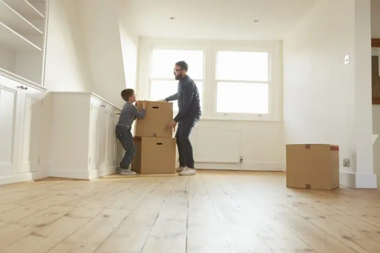 Mid adult man and son stacking cardboard box in new home