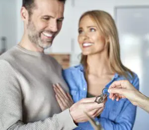 Smiling couple recieving keys to their new home
